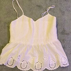 A white, flared, adjustable strapped, slight crop top that is not see through